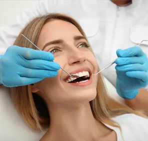 Woman's teeth being examined by a dentist at a dental care clinic.
