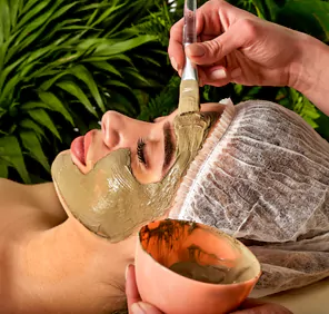 During ayurvedic massage therapy, herbal ingredients are applied on a woman's face.
