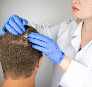 A haircare professional checks a man's scalp during PRP treatment in Hyderabad.
