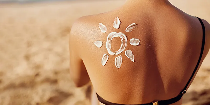 How to protect skin from sun tan - Woman with cream on her back to protect her skin from Sun damage.