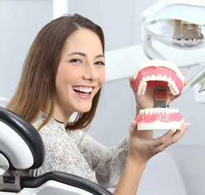 Woman holding dentures at a dental care clinic.
