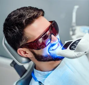 Man getting professional teeth whitening at an advanced dental clinic.
