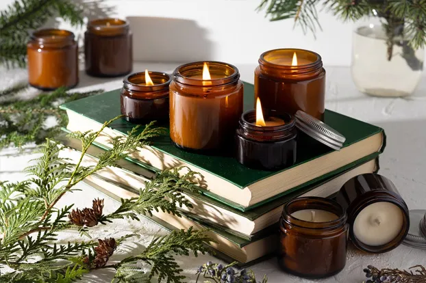 Scented candles on books, with plants around, for Aroma massage.
