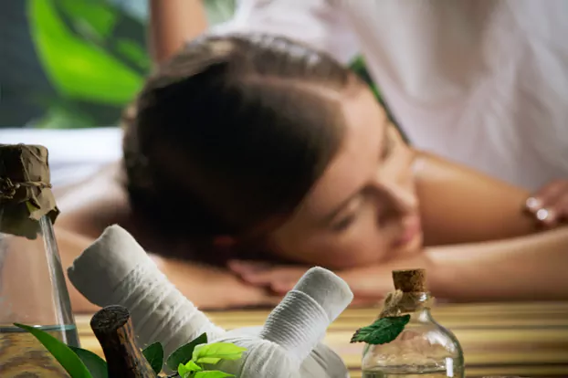 At an ayurvedic body massage center, a woman relaxes in the foreground.
