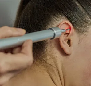 Woman getting laser treatment for facial hair on her ears.
