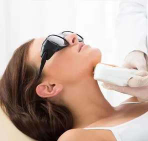 During a full body laser hair removal treatment, a white clinical instrument is hovering over a woman. 
