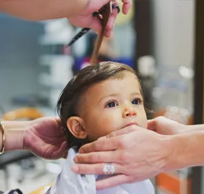 A small boy at a salon getting a haircut.
