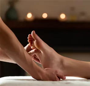 A therapist massaging the feet of a client during a Padabhyanga ayurvedic body massage.