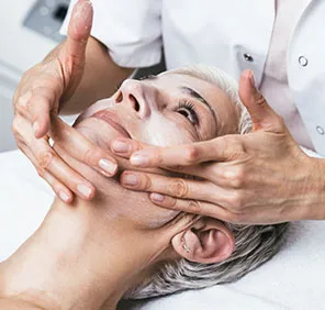 A woman with white hair is massaged with a white solution on her face during an anti aging treatment in Hyderabad.
