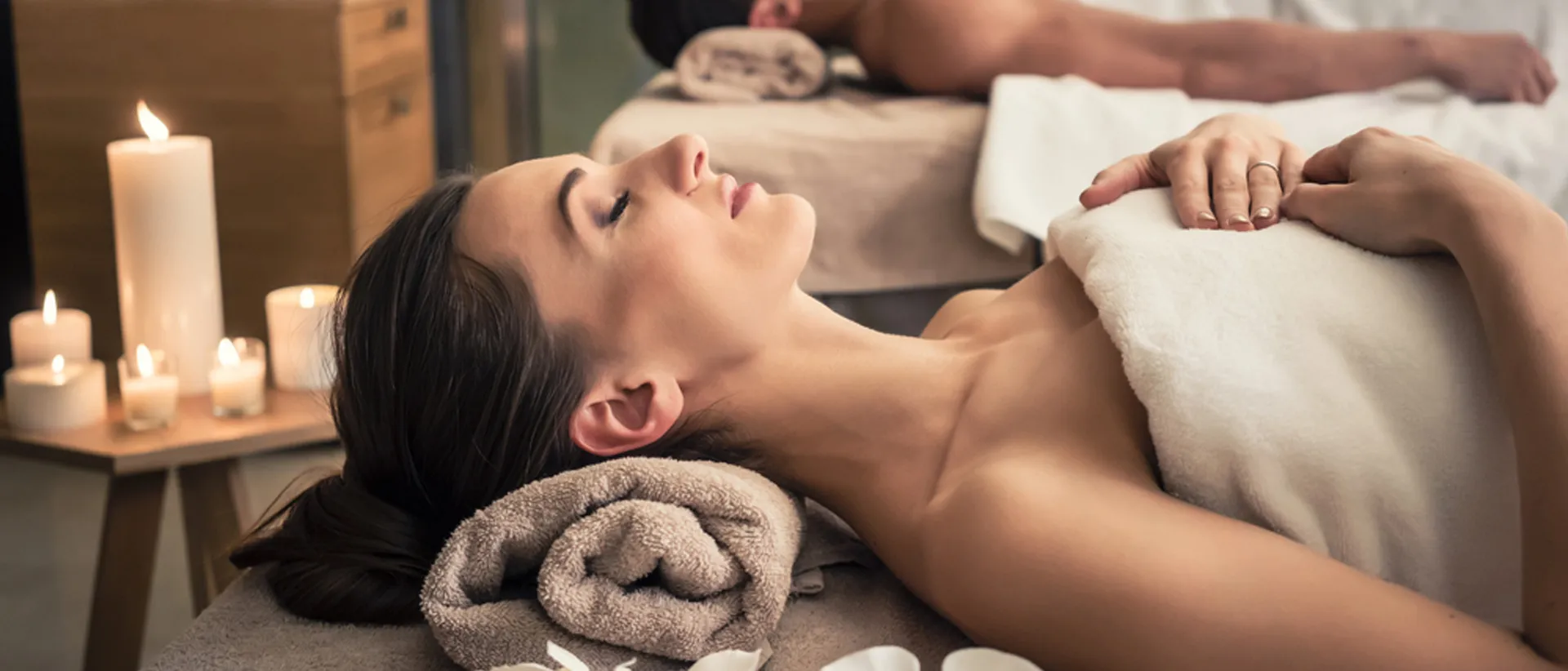 Woman relaxing at a massage spa with candles in the background.
