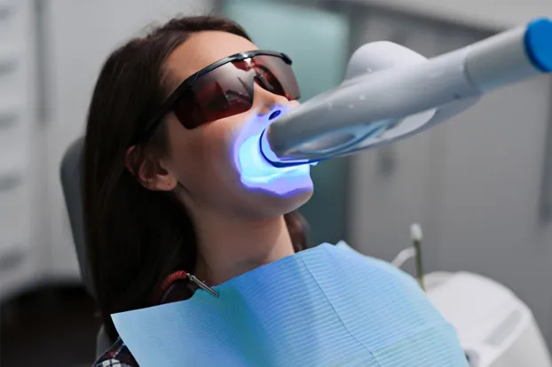 Woman getting teeth whitening at a dental clinic
