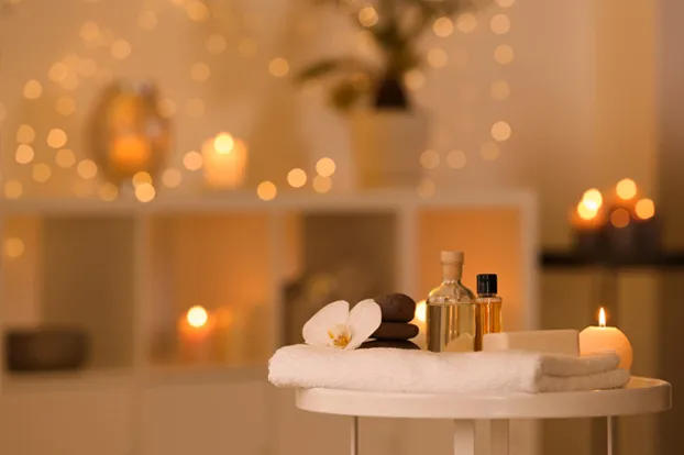Massage spa interiors with a flower, candle, oil and towel on a table
