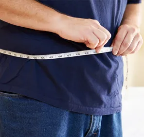 A person measuring waist size at a weight loss center near Hyderabad.
